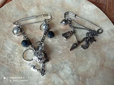 Pair Of Safety Pin Brooches With Charms- Silver Tone Black/ Gunmetal Tone  • £9.99
