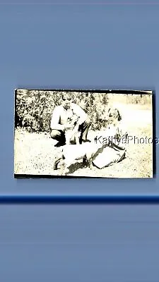 Found Vintage Photo D_6694 Man Crouching On Ground Holding Dog By Woman Sitting • $6.98